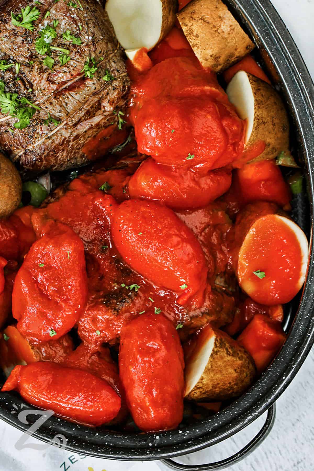 adding whole tomatoes to Best Pot Roast with potatoes and carrots