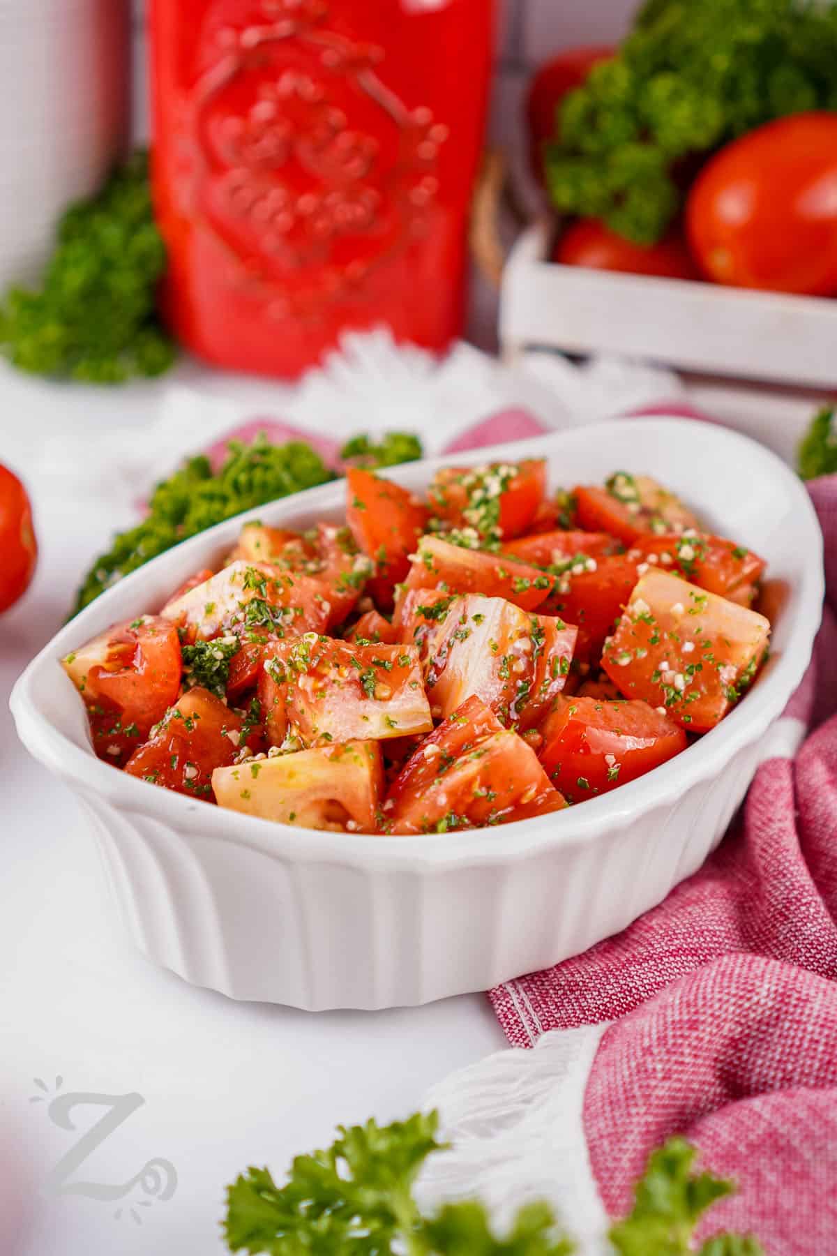 Marinated tomatoes are a fresh and flavorful way to enjoy ripe summer tomatoes. Roma tomatoes soak up a simple blend of olive oil, lemon juice, garlic, parsley, and salt for a bright side dish that pairs with almost any meal. They are delicious served with grilled meats, sandwiches, pasta, or toasted bread. Add this easy tomato recipe to your summer menu and give it a try. #ourzestylife juicy Marinated Tomatoes in a dish