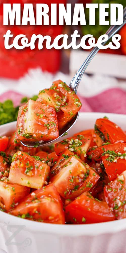 Fresh marinated tomatoes are an easy way to make ripe tomatoes the star of the table. Roma tomatoes are paired with lemon, garlic, parsley, and olive oil to create a bright marinade that adds flavor without overpowering the tomatoes. This simple side is perfect for summer dinners, backyard meals, and casual gatherings. Pick up some ripe tomatoes and make this recipe today. #ourzestylife dish of Marinated Tomatoes with some on a spoon with a title