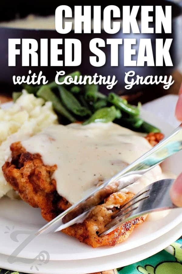 chicken fried steak with country gravy on a white plate, and a knife and fork cutting off a slice, with a title