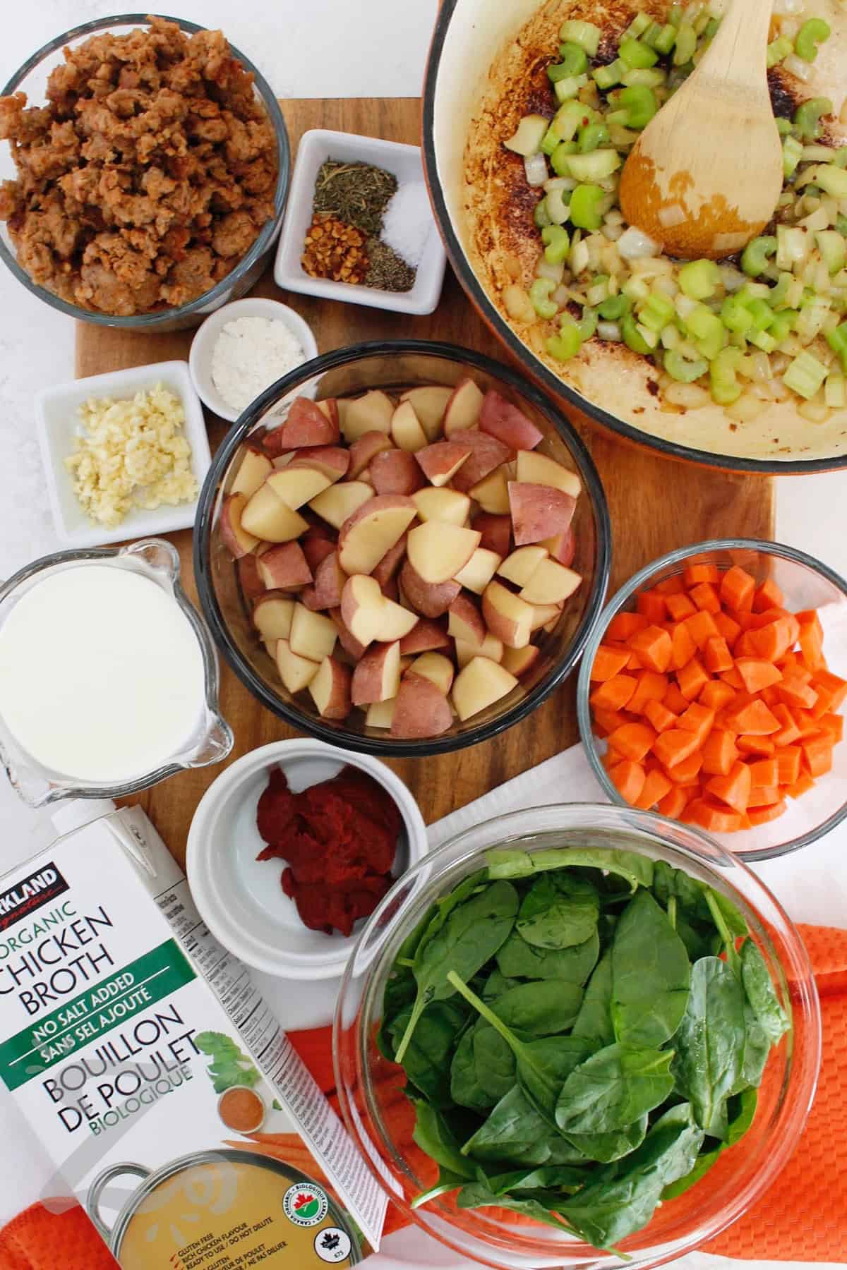 Make dinner cozy with this creamy Sausage Potato Soup. Tender red potatoes, carrots, celery, spinach, and Italian sausage come together in a flavorful chicken broth finished with cream and Parmesan. This sausage and potato soup is hearty enough to serve as a complete meal. Why not warm up with a bowl tonight? #ourzestylife process to make sausage potato soup where cooked sausage has been removed, and onion and celery are sauteed in the pot.
