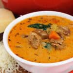 sausage potato soup in a white bowl with fresh shredded parmesan on the side.