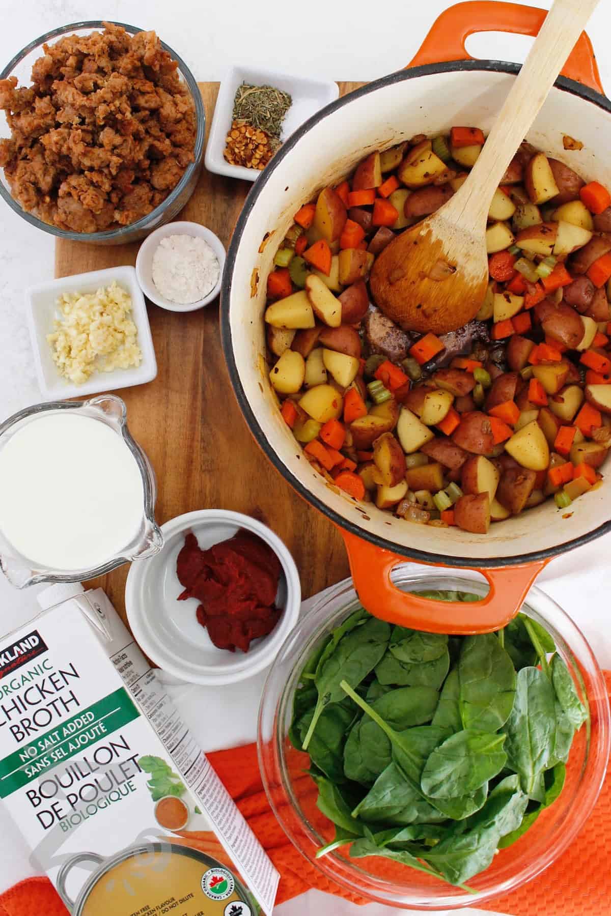 If you love hearty homemade soups, this Sausage Potato Soup belongs on your list. Italian sausage, potatoes, carrots, celery, and spinach simmer in a savory broth with Italian herbs, tomato paste, and cream. This flavorful dish is easy enough for a weeknight so give it a spot on your dinner table this week! #ourzestylife process to make sausage potato soup when onion, celery, carrots, and potatoes have been added to the pot.