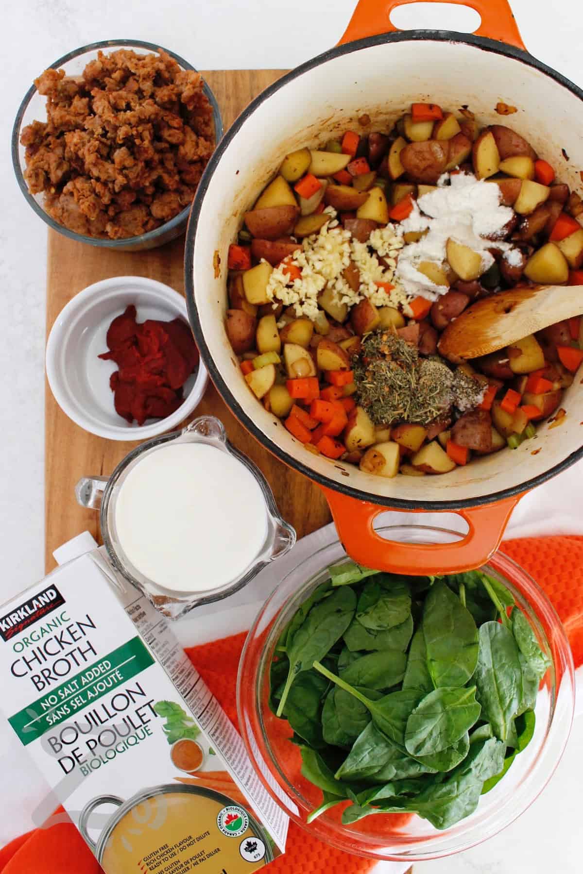 A bowl of sausage and potato soup is just what you need on a chilly evening. Savory Italian sausage, tender potatoes, fresh vegetables, and spinach are combined with a creamy, herb filled broth and a touch of red pepper. This soup makes simple, satisfying comfort food that you will love. Why not make it tonight? #ourzestylife process to make sausage potato soup when seasonings, garlic, and flour are added to the vegetables.